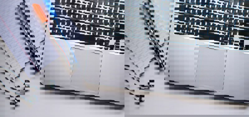 Laptop met daarnaast notitieblok en pennen